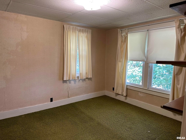 empty room featuring a drop ceiling and dark colored carpet