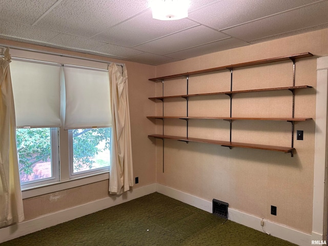 carpeted spare room featuring a drop ceiling