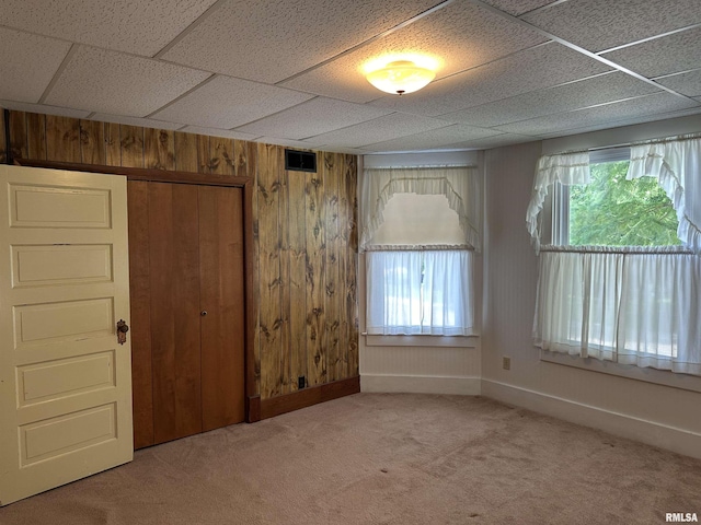 212 S Broadway St, Stronghurst, IL 61480 - unfurnished room with carpet flooring, baseboards, a drop ceiling, wooden walls, and visible vents