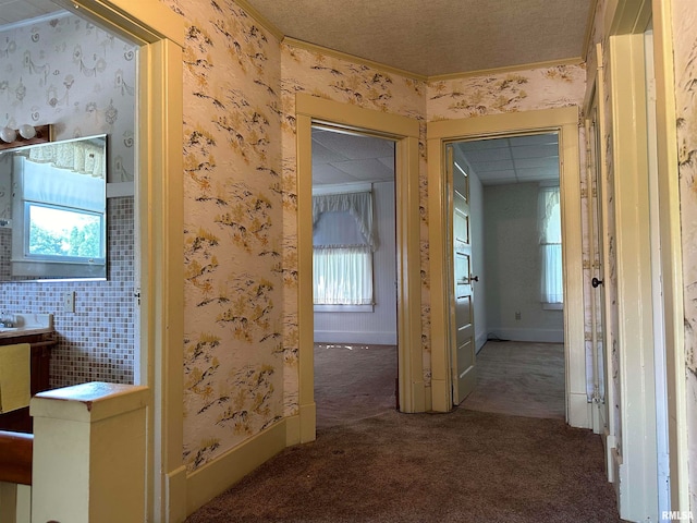 corridor with dark colored carpet and a textured ceiling