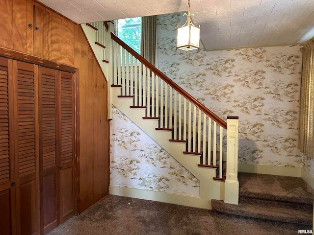 staircase featuring carpet floors and wood walls