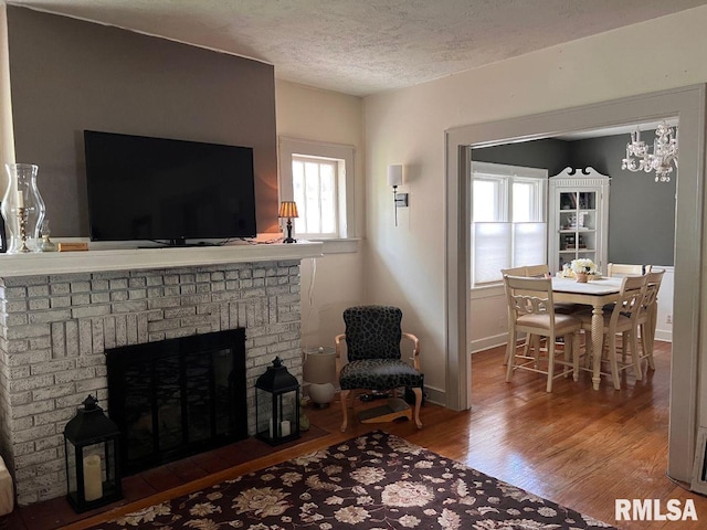 living room with hardwood / wood-style flooring, a chandelier, a textured ceiling, and a fireplace