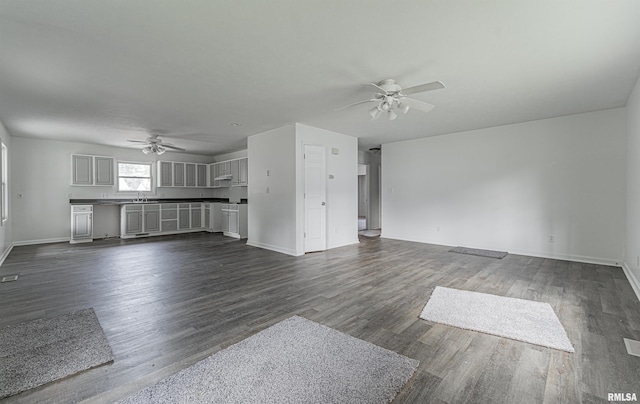 unfurnished living room with dark hardwood / wood-style flooring, sink, and ceiling fan