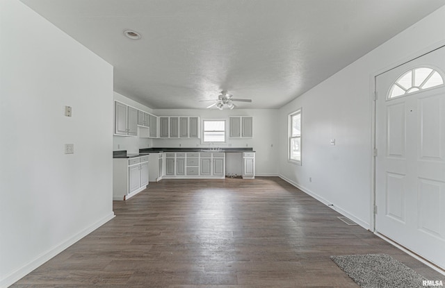 unfurnished living room featuring sink, dark hardwood / wood-style floors, and ceiling fan