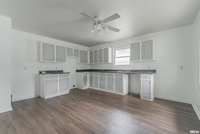 kitchen with sink, dark wood-type flooring, gray cabinets, and ceiling fan