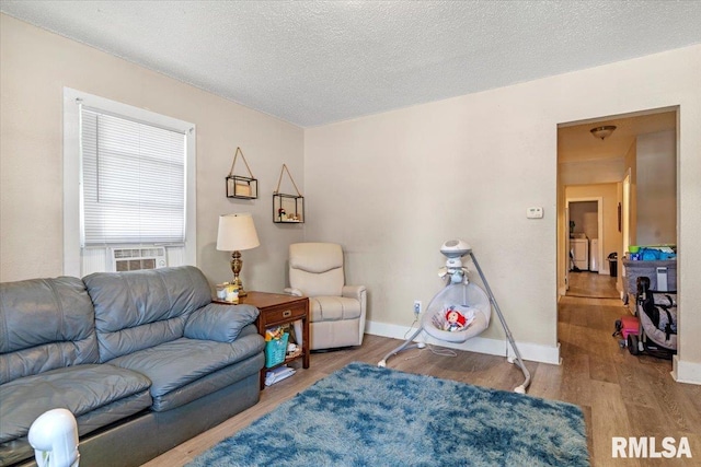 living room with cooling unit, wood-type flooring, and a textured ceiling