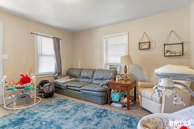 living room featuring hardwood / wood-style floors, cooling unit, a textured ceiling, and a wealth of natural light