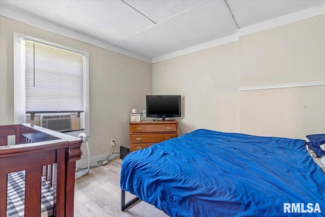 bedroom featuring light hardwood / wood-style flooring, cooling unit, and ornamental molding