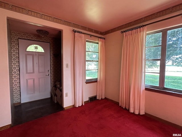 entryway featuring baseboards, visible vents, and dark colored carpet