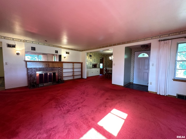 unfurnished living room featuring visible vents, carpet floors, and a brick fireplace