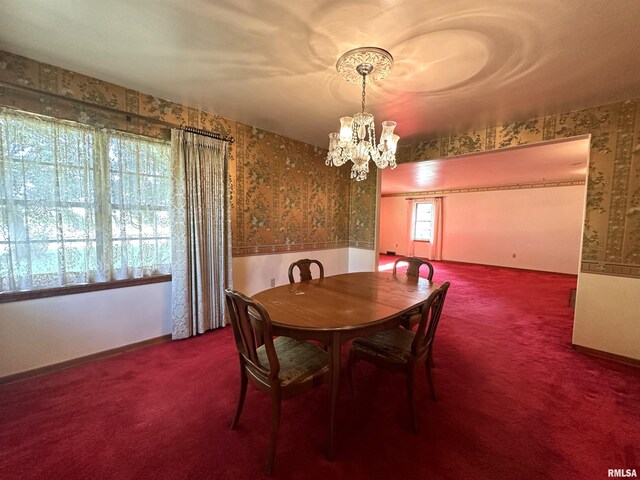 carpeted dining area featuring a notable chandelier and wallpapered walls