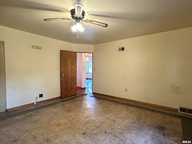 empty room featuring visible vents, a ceiling fan, and baseboards