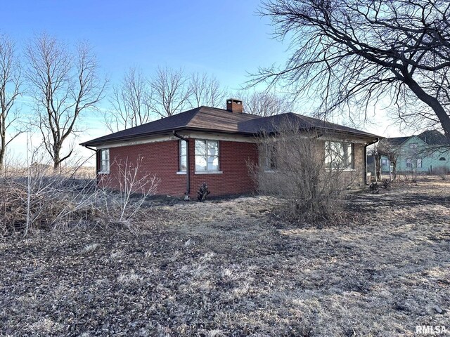 view of side of property with brick siding and a chimney