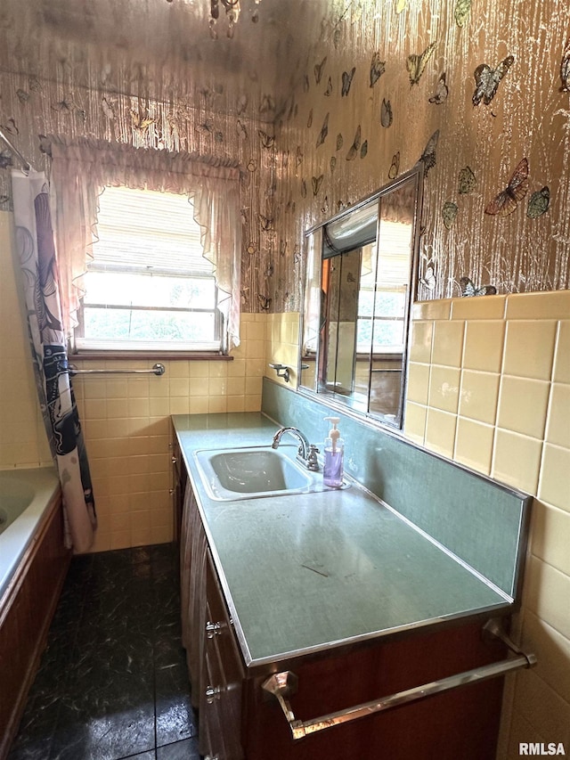 kitchen with a sink, tile walls, light countertops, and wallpapered walls