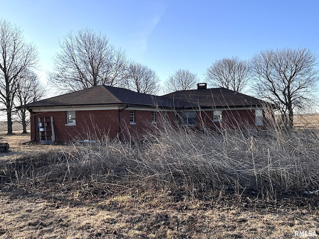 view of property exterior with brick siding and a chimney