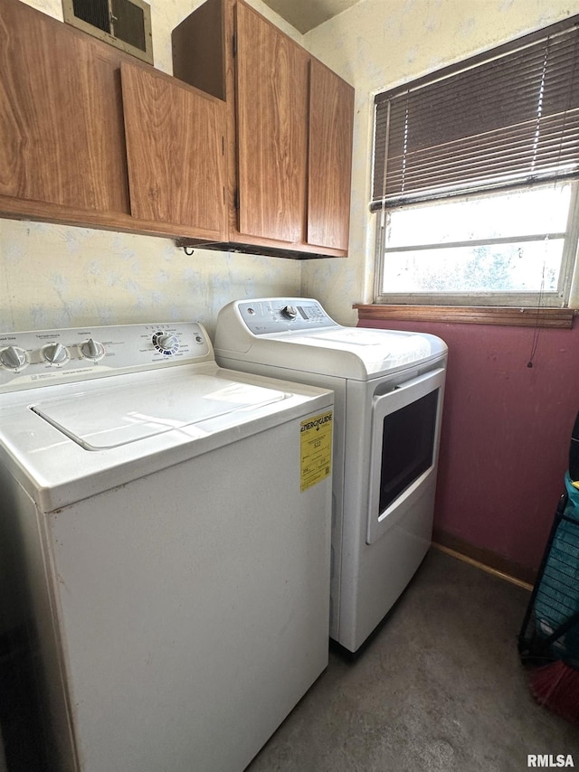 clothes washing area with cabinet space, visible vents, and washer and dryer