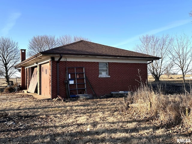 view of home's exterior with brick siding, roof with shingles, and a chimney