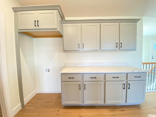 kitchen with gray cabinets, light hardwood / wood-style floors, and light stone counters