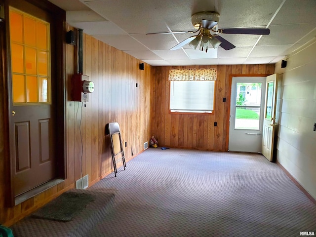 unfurnished room with ceiling fan, wooden walls, and carpet