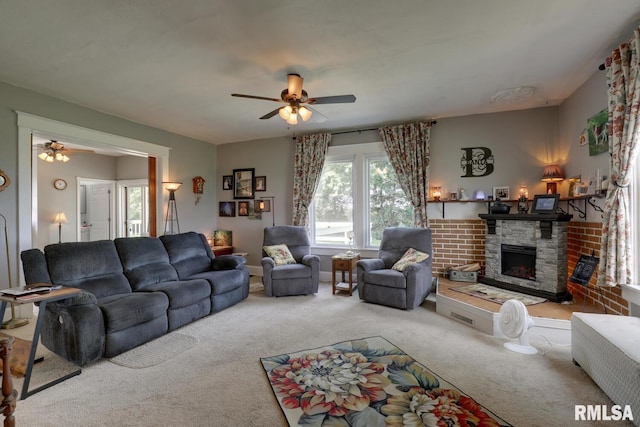 carpeted living room with ceiling fan and a stone fireplace