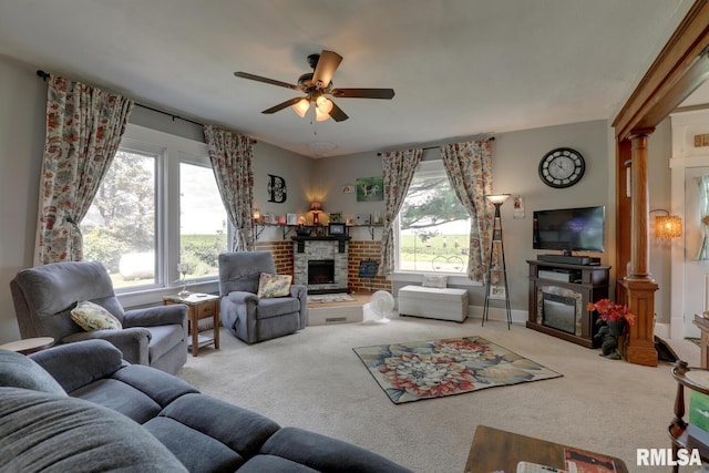 living room with ceiling fan, ornate columns, carpet floors, and a brick fireplace