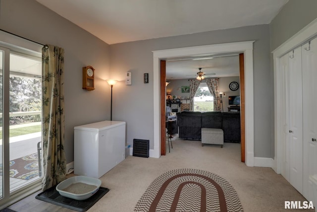 interior space with ceiling fan and light carpet