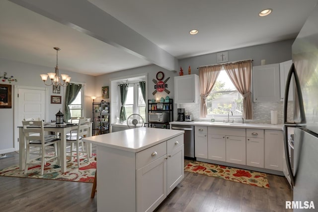 kitchen featuring tasteful backsplash, white cabinets, stainless steel appliances, and hardwood / wood-style flooring