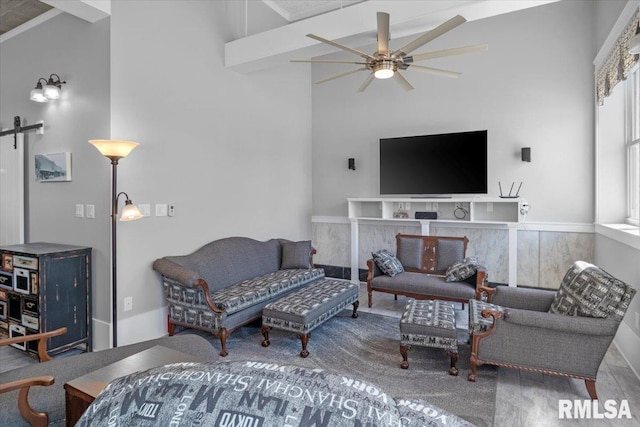 living room with a barn door, ceiling fan, a high ceiling, and hardwood / wood-style flooring