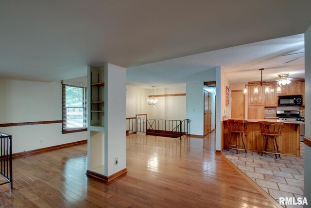 living room featuring ceiling fan with notable chandelier and light hardwood / wood-style floors