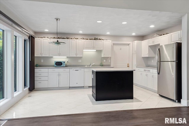 kitchen with light wood-type flooring, white cabinetry, sink, decorative light fixtures, and stainless steel appliances