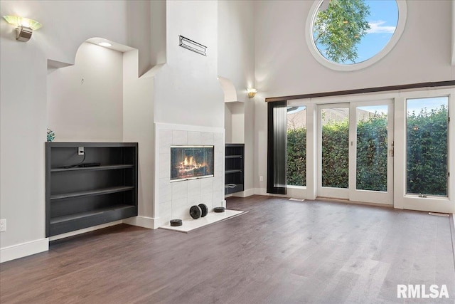 unfurnished living room featuring hardwood / wood-style flooring, a high ceiling, and a tile fireplace