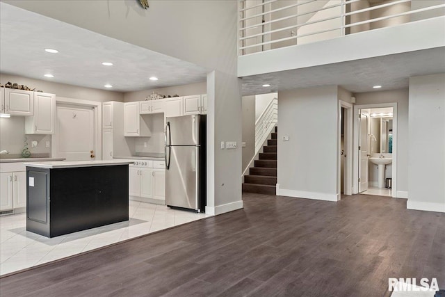 kitchen featuring white cabinets, light wood-type flooring, stainless steel fridge, and a center island