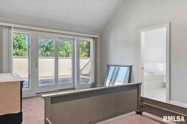 bedroom featuring carpet floors, vaulted ceiling, ensuite bath, and multiple windows