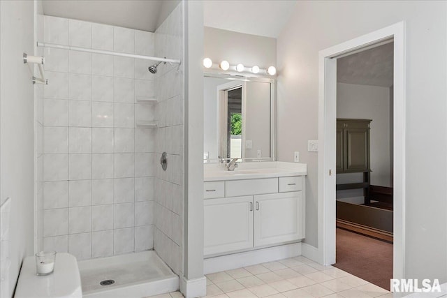 bathroom with tile patterned flooring, a tile shower, and vanity