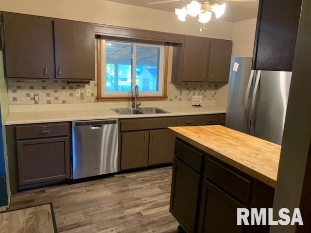 kitchen with tasteful backsplash, light wood-type flooring, butcher block counters, sink, and stainless steel appliances