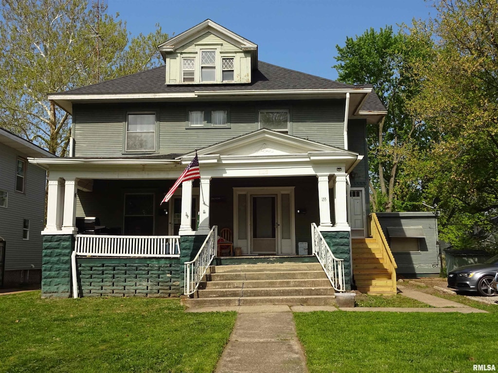 american foursquare style home with a porch, a front yard, and a shingled roof