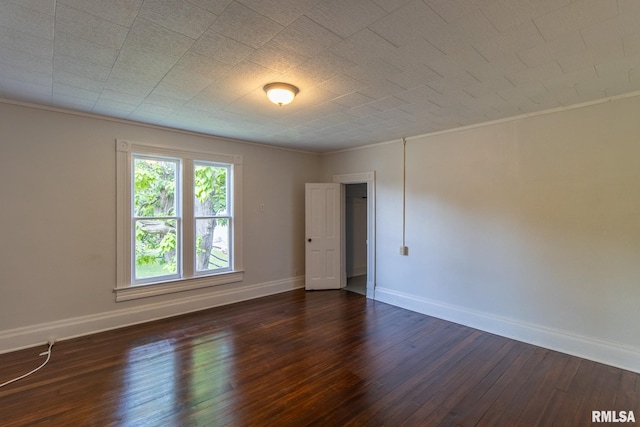 empty room with crown molding and dark hardwood / wood-style flooring