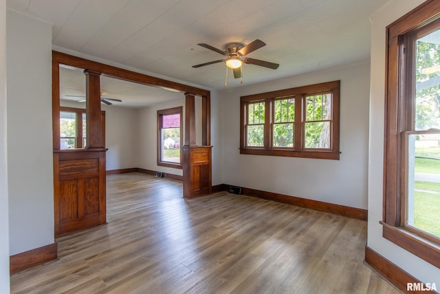 empty room with a wealth of natural light, ceiling fan, and hardwood / wood-style flooring