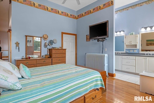 bedroom with radiator, ceiling fan, light hardwood / wood-style flooring, and sink