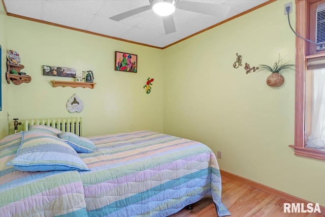 bedroom with ceiling fan, radiator heating unit, ornamental molding, and hardwood / wood-style flooring