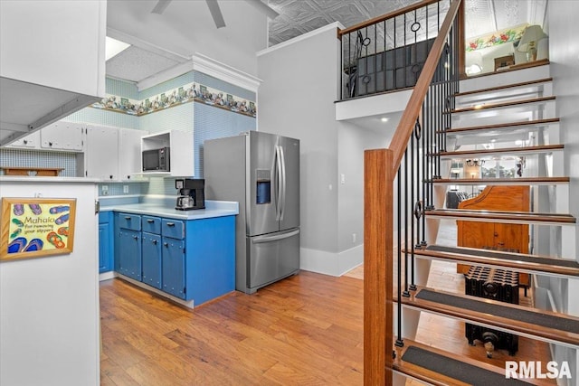 kitchen with blue cabinets, decorative backsplash, ornamental molding, light hardwood / wood-style floors, and stainless steel fridge with ice dispenser