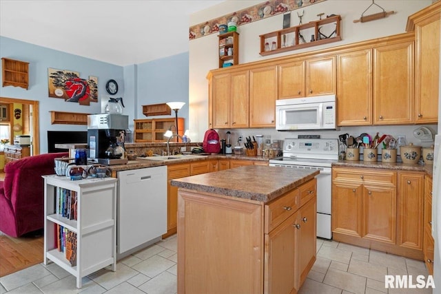 kitchen featuring light wood-type flooring, white appliances, sink, light brown cabinets, and a kitchen island