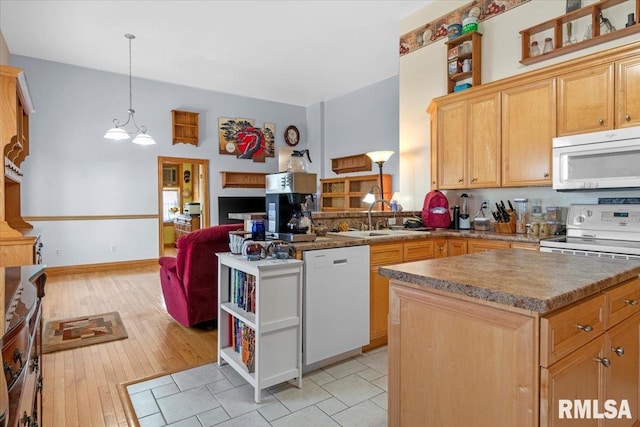 kitchen featuring sink, a notable chandelier, white appliances, a kitchen island, and light wood-type flooring