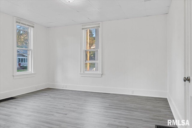 spare room with hardwood / wood-style floors, a wealth of natural light, and a paneled ceiling