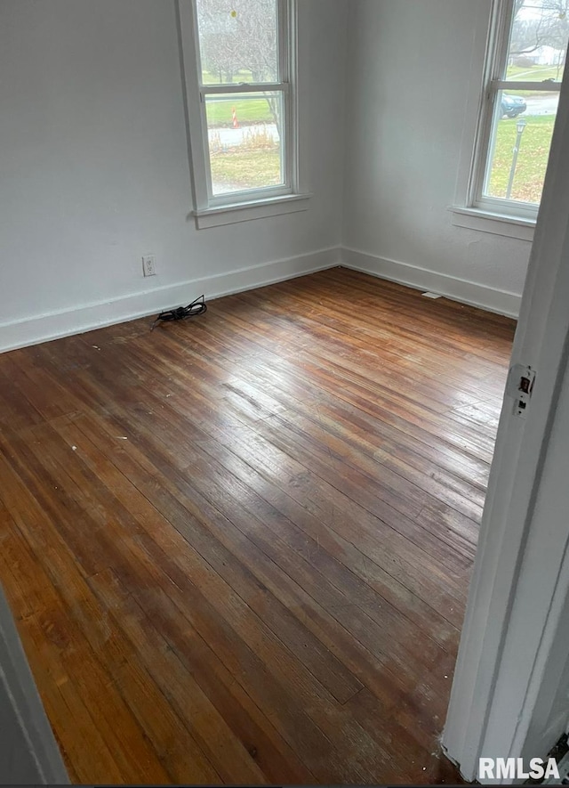 spare room with plenty of natural light and dark wood-type flooring