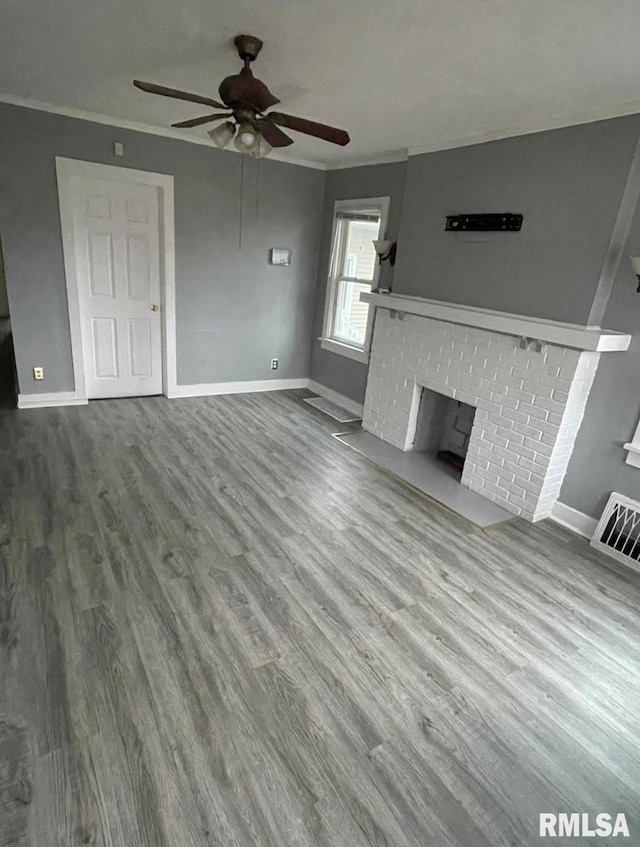 unfurnished living room with crown molding, ceiling fan, wood-type flooring, and a fireplace