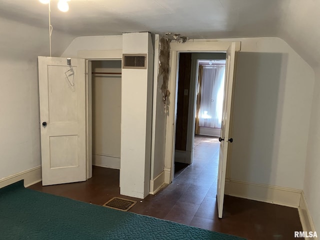 unfurnished bedroom featuring vaulted ceiling and a closet