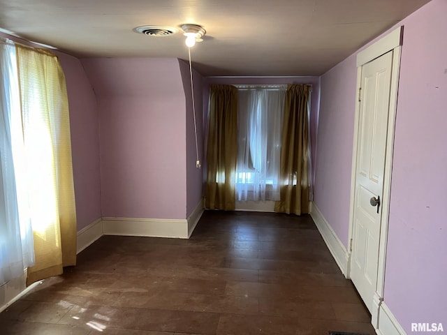 spare room featuring dark wood-type flooring, a healthy amount of sunlight, and vaulted ceiling