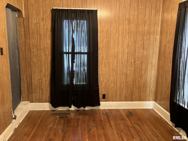 spare room with wood-type flooring and wooden walls