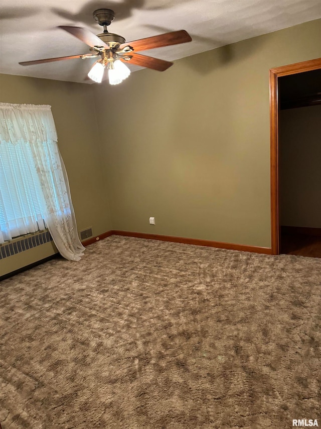 spare room with carpet flooring, ceiling fan, and radiator